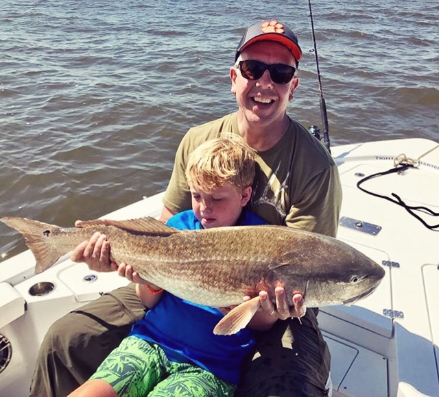 Father and young child holding a huge spot tail in the Charleston harbor