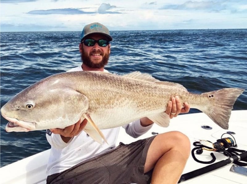 Captain Jesse Riddle holding huge spot tail on his 33' Contender boat