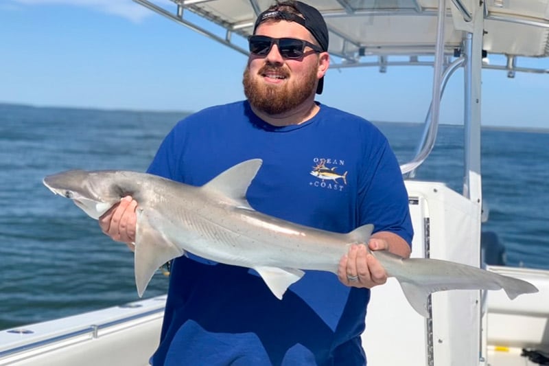 Man holding a large shark he caught in Charleston Harbor