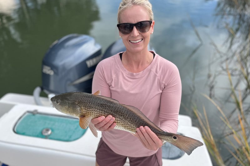 Woman holding spottail bass during inshore fishing charter in Charleston