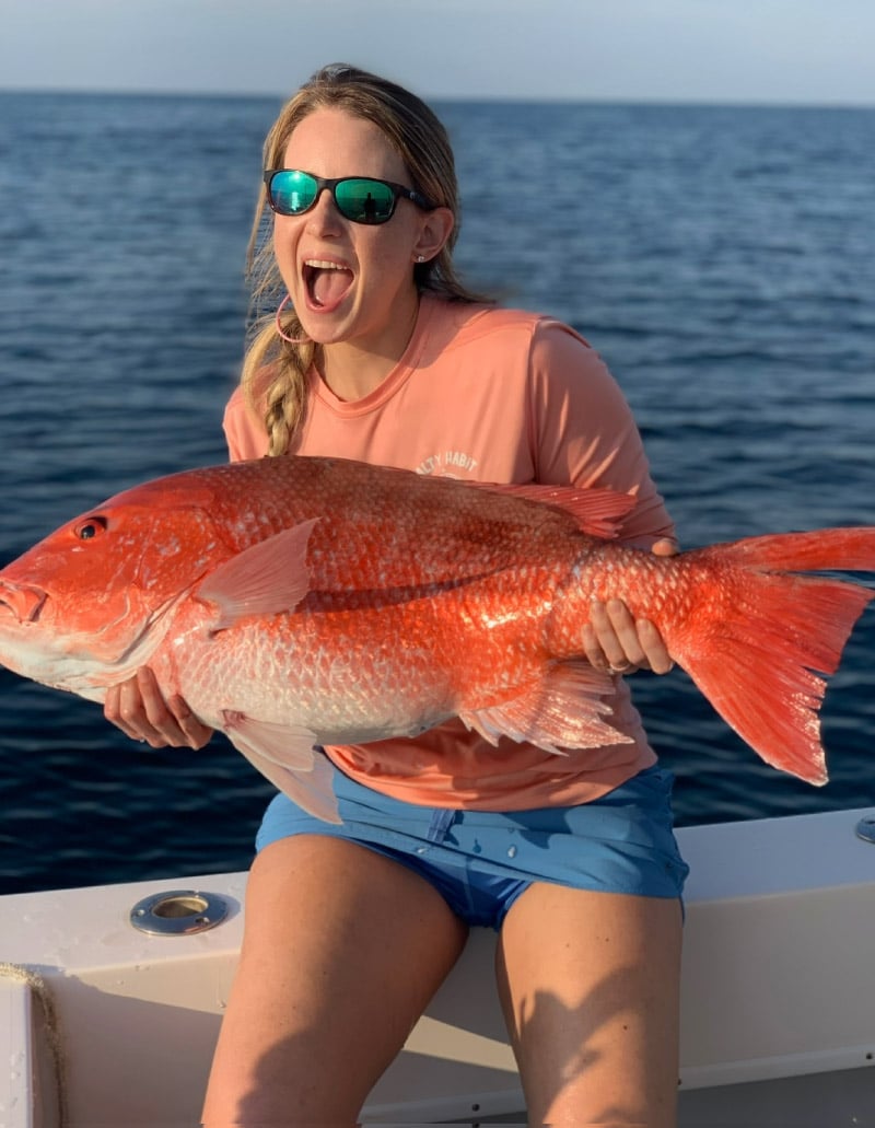 Smiling woman holding large fish caught in Charleston