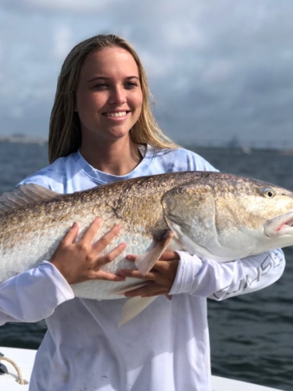 Happy woman holding bull red during Charleston fishing trip