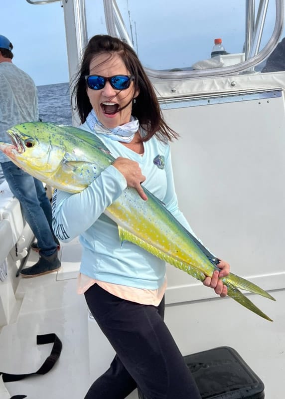 Woman holding large Mahi caught during offshore fishing trip