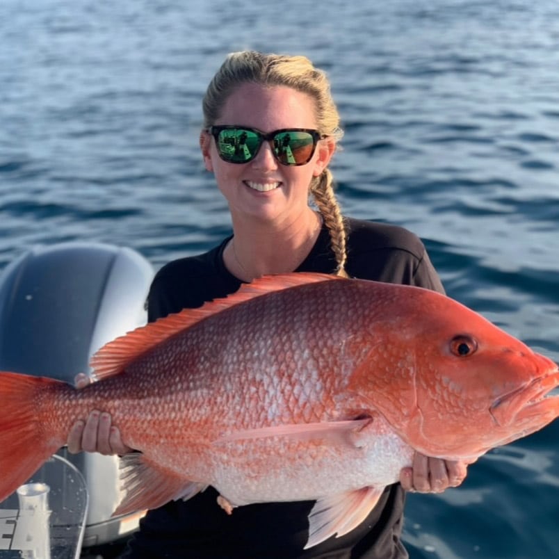 Young woman holding red snapper she caught during nearshore fishing trip in Charleston