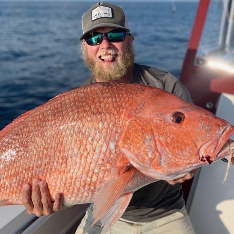 Man holding large red snapper she caught during nearshore fishing trip in Charleston